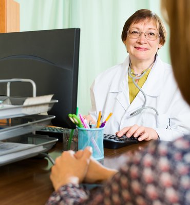 zdravnica za računalnikom se pogovarja s pacientko